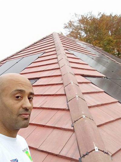 Ashley installing solar panels on a red slate roof